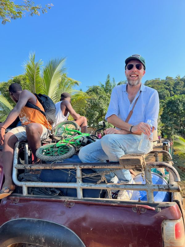 Felix sitzt lachend auf einem rostigen Auto