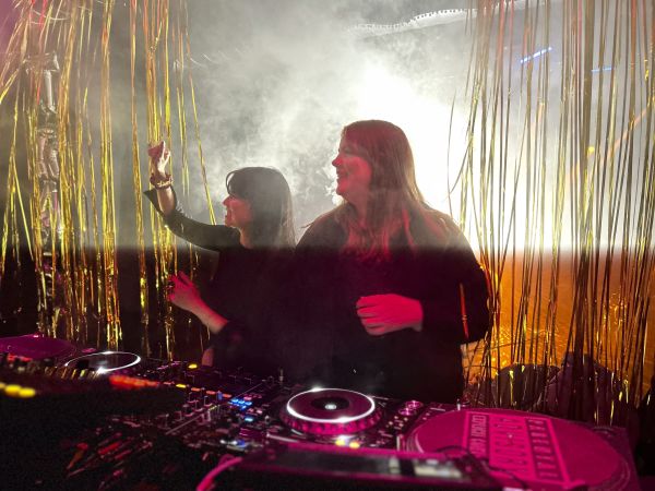 Roberta und ihre Freundin hinter dem Mischpult, das vor einem Lamettavorhang steht