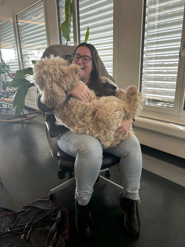 Sandra sitzt auf dem Bürostuhl mit einem grossen Hund auf dem Schoss
