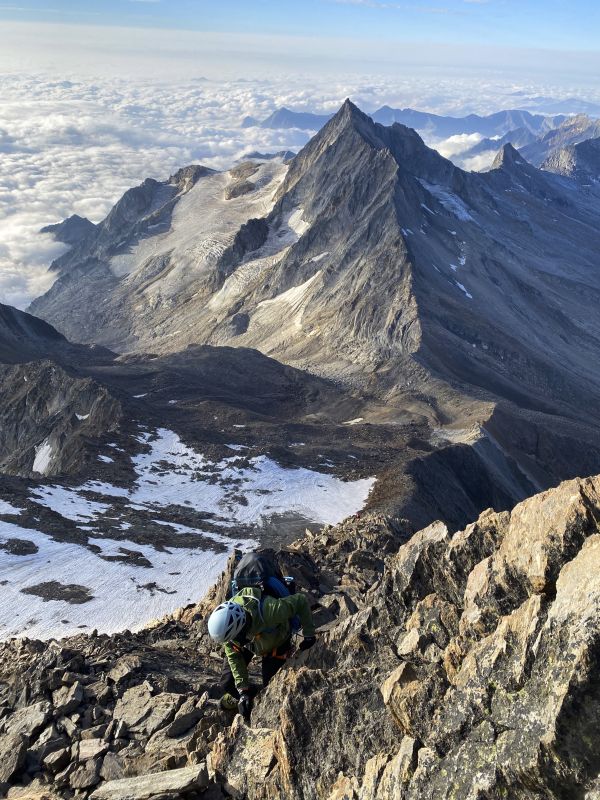 Bergpanorama und Mann, der auf die Bergspitze klettert