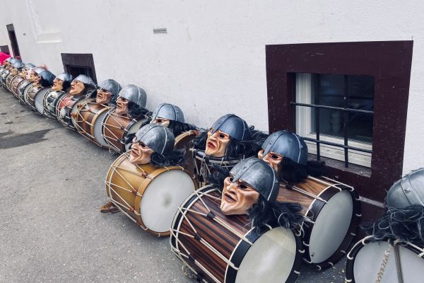 Trommeln und Masken der Fasnacht liegen aufgereiht auf dem Boden